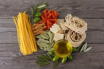 Different kinds of of pasta on the wooden background. Spaghetti. Olive oil.
