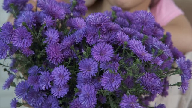 Happy mother with daughter with flowers. Little girl with mom with mom with lilac chrysanthemums.