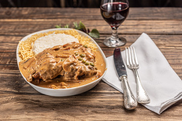 Beef with mushroom, rice and potato in a white plate on wooden white background. Soft light. Italian food.