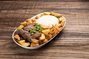 Beef steak with rustic potato and ricei on wooden table background, soft light