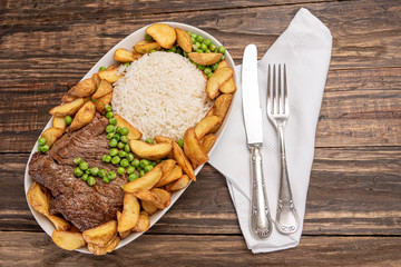 Beef steak with rustic potato and ricei on wooden table background, soft light
