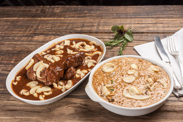 Risotto with filet mignon. Risoto and beef with mushroom in a white plate on wooden white background. Soft light. Italian food.