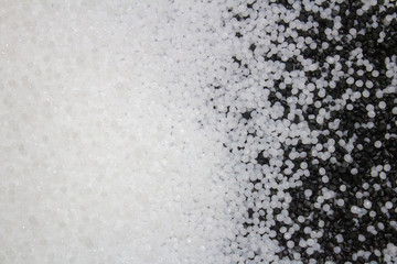 surface of white plastic granules with mixing black granules on the right.