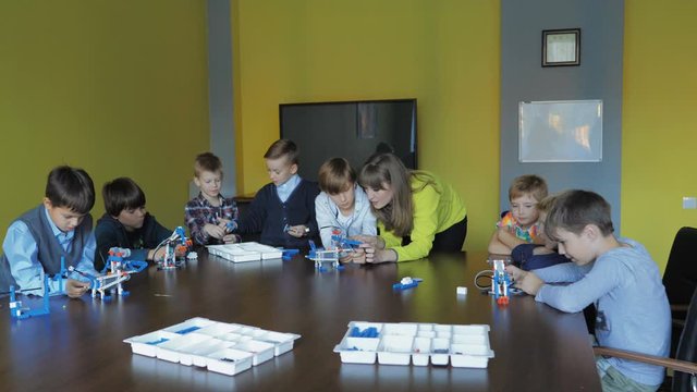 Kids creating figures with teacher. Early development, modern technology concept