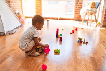 Beautiful african american toddler playing with tractor toy at kindergarten