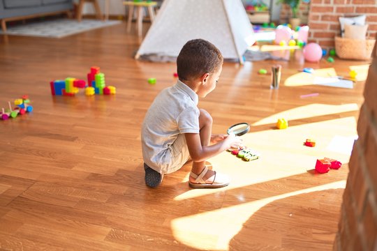 Beautiful african american toddler playing with cars around lots of toys at kindergarten