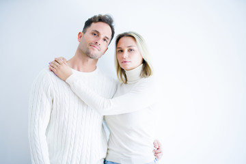 Young beautiful couple wearing casual t-shirt standing over isolated white background with serious expression on face. Simple and natural looking at the camera.