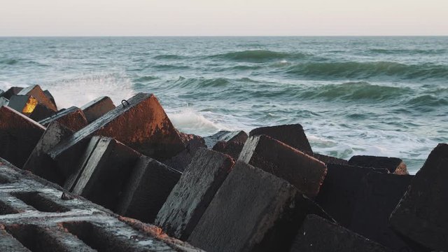 Sea waves in a storm on a cold day, slow motion . Ocean waves are breaking on a breakwater at sunset
