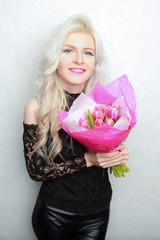 tender pretty blonde slim teen girl with pink flowers. cheerful woman with fresh bouquet