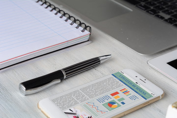 Office desk table with smartphone screen with statistics about company growth