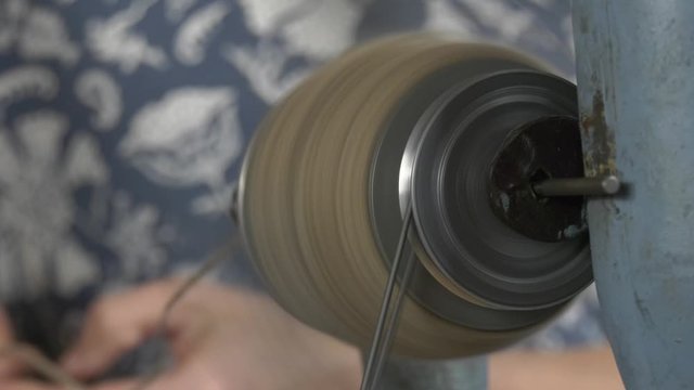 Rotating spindle in a manual woolen lock during operation. Extra close-up hand-operated spindle parts in action.