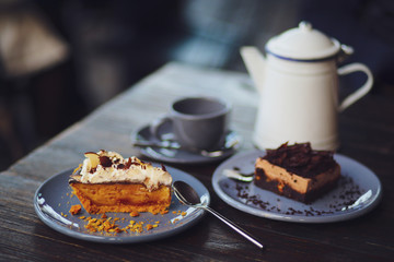 A metal teapot with rose tea in a restaurant. Tea party with chocolate dessert in a cafe. Vitamin raspberry tea with mint and cheesecake. Sweets, desserts with a hot drink.Gray dishes and wooden table