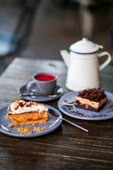 A metal teapot with rose tea in a restaurant. Tea party with chocolate dessert in a cafe. Vitamin raspberry tea with mint and cheesecake. Sweets, desserts with a hot drink.Gray dishes and wooden table