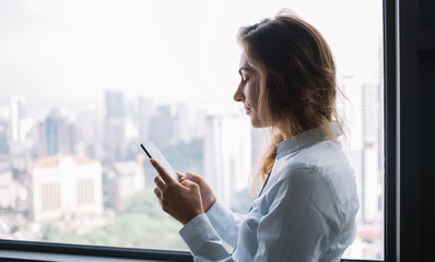 Fototapeta premium Young adult lady chatting on phone nearby window