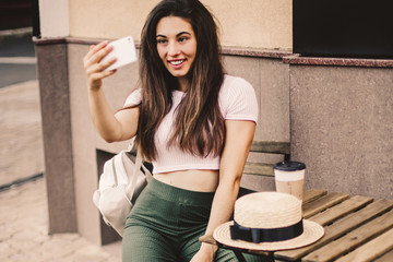 Beautiful woman using phone and drink coffee sitting on street cafe.