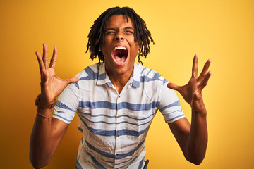 Afro american man with dreadlocks wearing striped shirt over isolated yellow background celebrating...