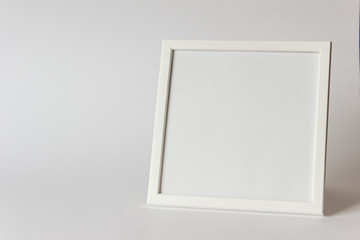 Mockup of white square picture frame with white paper on white background. Photo with copy blank space.