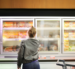 Woman choosing frozen food from a supermarket freezer	