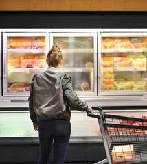 Woman choosing frozen food from a supermarket freezer	