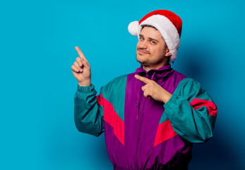 Fototapeta na wymiar Handsome man in Christmas hat and 90s jacket on blue background