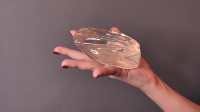 Silicone breast implant surgery gel type and smooth skin surface in hand compression test, medical equipment used in clinic or hospital.