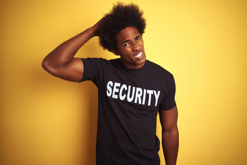 American safeguard man with afro hair wearing security uniform over isolated yellow background...