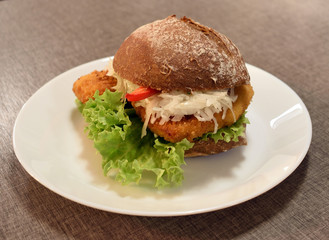 Bun with schnitzel, pepper and lettuce leaves