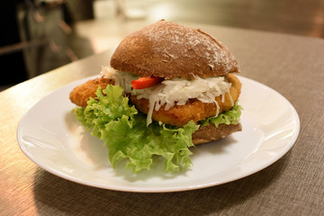 Bun with schnitzel, pepper and lettuce leaves