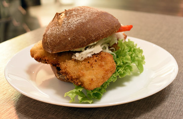 Bun with schnitzel, pepper and lettuce leaves