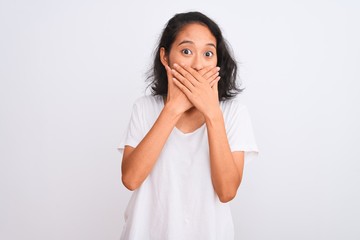 Young chinese woman wearing casual t-shirt standing over isolated white background shocked covering mouth with hands for mistake. Secret concept.