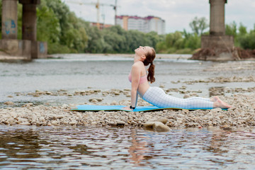 healthy girl relaxing while meditating and doing yoga exercise in the beautiful nature on the bank of the river