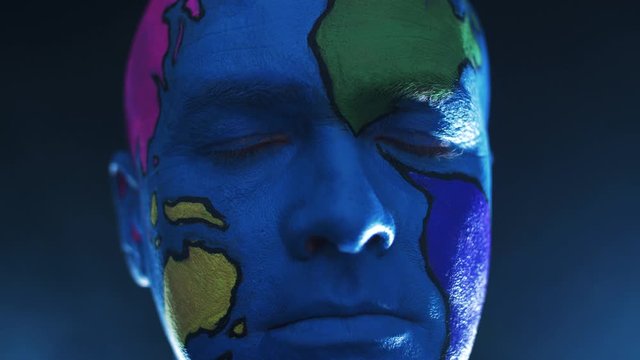 the beautiful make-up of a planet of the earth with colored continents on a bald man, who opens his eyes and looks at the camera.
