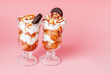 Sweet dessert in glass with biscuit and whipped cream on pink bsckground, selective focus and blank space