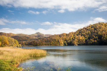 Fototapeta premium A calm evening landscape with lake and mountains. Amazing view of the Goy-Gol (Blue Lake) Lake among colorful fall forest at Ganja, Azerbaijan.