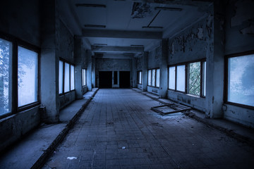 Dark, spooky tunnel, corridor with large windows at the end in abandoned building