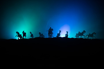 Medieval battle scene with cavalry and infantry. Silhouettes of figures as separate objects, fight between warriors on dark toned foggy background. Night scene.