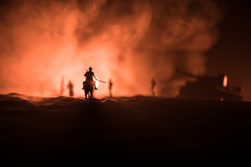 World war officer (or warrior) rider on horse with a sword ready to fight and soldiers on a dark foggy toned background. Battle scene battlefield of fighting soldiers.