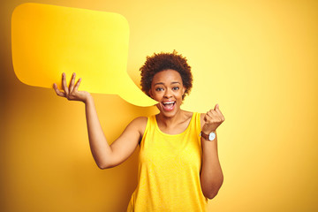 Young african american woman holding speech bubble over yellow isolated background screaming proud and celebrating victory and success very excited, cheering emotion