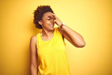 Beauitul african american woman wearing summer t-shirt over isolated yellow background smelling...