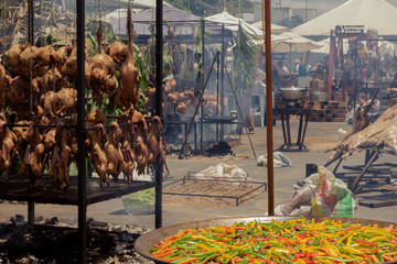 a big pan of paella in front of a lot of clotheslines of meat