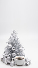 A christmas (new year) close up white cup of coffee and silver christmas tree on white background