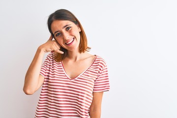 Fototapeta premium Beautiful redhead woman wearing casual striped red t-shirt over isolated background smiling doing phone gesture with hand and fingers like talking on the telephone. Communicating concepts.
