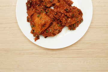 Deep fried fish paste balls served on white plate set on wooden