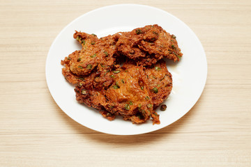 Deep fried fish paste balls served on white plate set on wooden