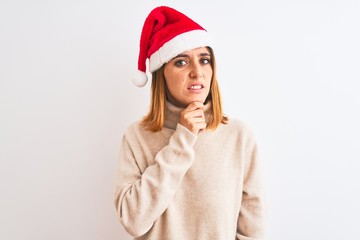Beautiful redhead woman wearing christmas hat over isolated background Thinking worried about a question, concerned and nervous with hand on chin
