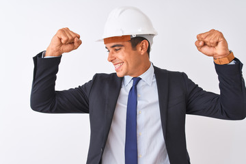 Young handsome architect man wearing suit and helmet over isolated white background showing arms muscles smiling proud. Fitness concept.