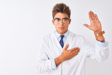 Young handsome sciencist man wearing glasses and coat over isolated white background Swearing with...