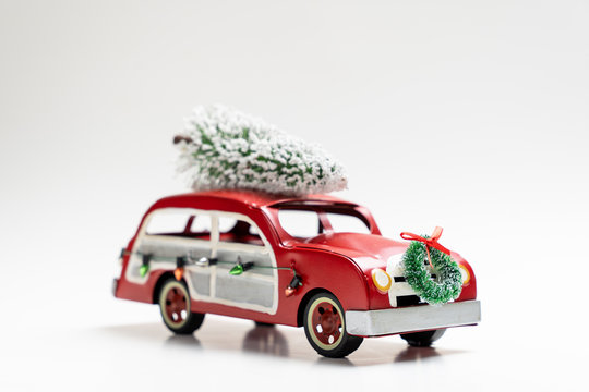 Miniature red vintage car carrying a Christmas tree on top for Xmas theme