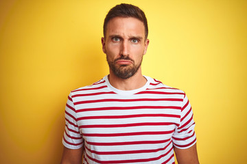 Obraz premium Young handsome man wearing casual red striped t-shirt over yellow isolated background depressed and worry for distress, crying angry and afraid. Sad expression.