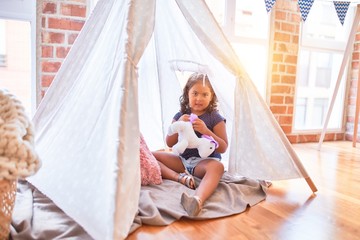 Beautiful toddler girl sitting on the floor playing with unicorn inside tipi at kindergarten © Krakenimages.com
